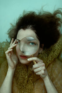 Close-up waterportrait of young woman holding a magnifier 