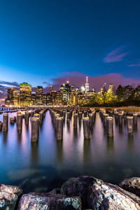 Illuminated bridge over river against sky in city at night