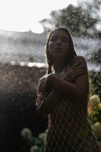 Portrait of young woman standing in the rain in the summer garden
