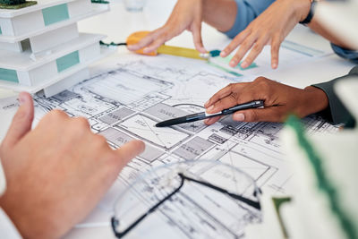 Midsection of architect working on blueprint