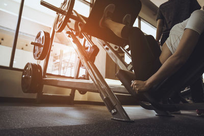 Low section of woman exercising by man in gym