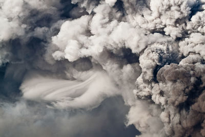 Smoke emitting from volcanic landscape against sky