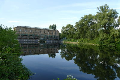 Reflection of building and trees in lake against sky