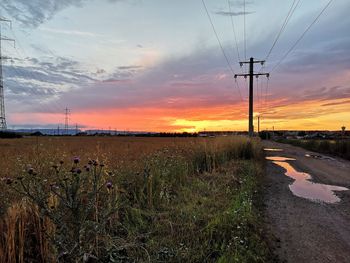 Electricity pylon on field against sky during sunset