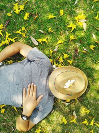 High angle view of man covering face with hat lying on grass