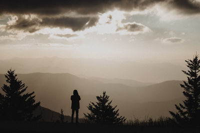 Silhouette man standing on mountain against sky