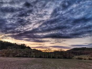 Scenic view of dramatic sky over land during sunset
