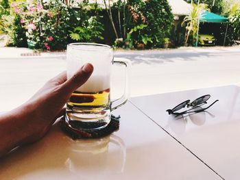 Close-up of hand holding wine glass on table