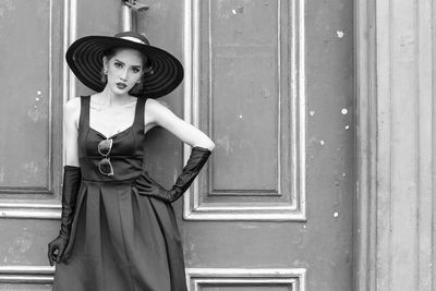 Portrait of woman standing against door