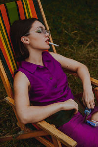 Woman smoking cigarette while sitting on chair