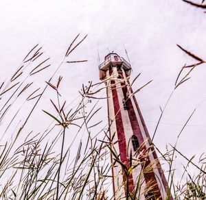 Low angle view of lighthouse by building against sky