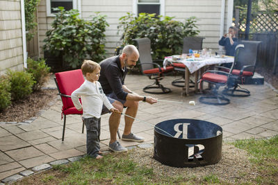 A father roasts marshmallows with his children in yard