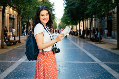 Portrait of smiling woman standing on street in city