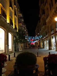 Illuminated street amidst buildings in city at night