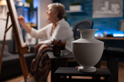 Gray vase on table with woman sketching at home