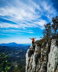 Rear view of person on rock against sky