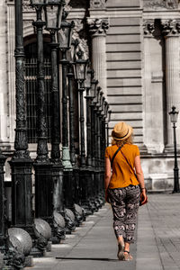 Full length rear view of woman walking against historic building