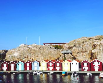 Buildings by river against clear blue sky