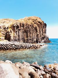 Rocks on shore against clear blue sky