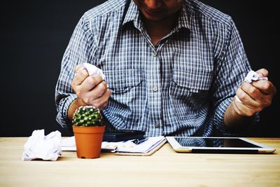 Midsection of businessman crumpling papers at desk in office