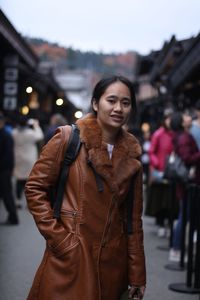 Portrait of woman in warm clothes standing on city street during winter