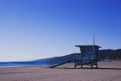 Lifeguard hut on beach against clear blue sky