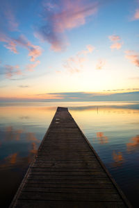 Pier over sea against sky during sunset