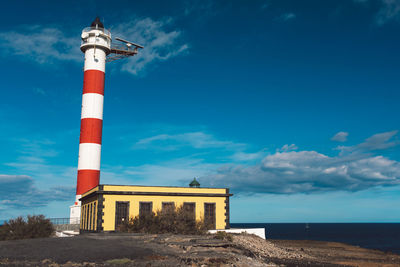 Lighthouse by sea against sky