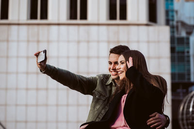 Boyfriend taking selfie with girlfriend over mobile phone outdoors