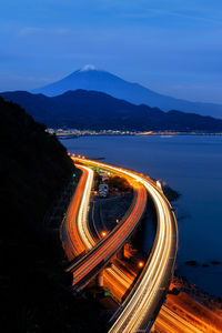 High angle view of light trails on road by mountain against sky