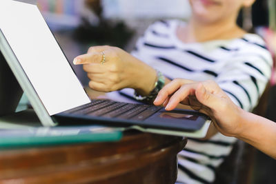 Midsection of woman using laptop computer on table