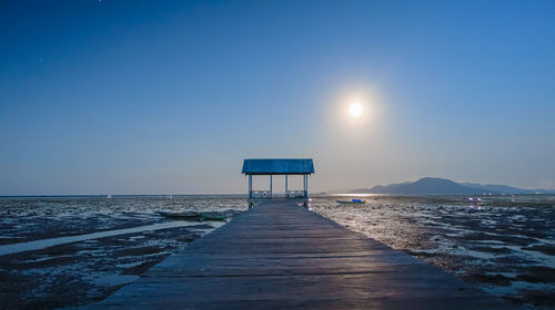 Pier over sea against clear blue sky