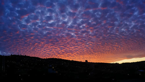 Silhouette landscape against dramatic sky during sunset