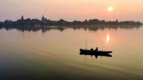 Silhouette boat in lake against sky during sunset