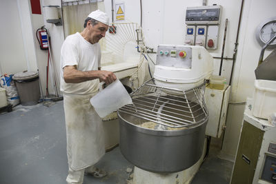 Baker pouring water in an industrial kneading machine