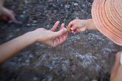 High angle view of woman hand and schild hand on rock