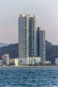 Modern buildings by sea against sky in city