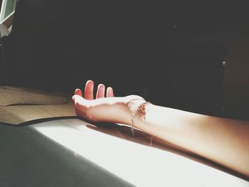 Cropped hand of woman on table in sunny day