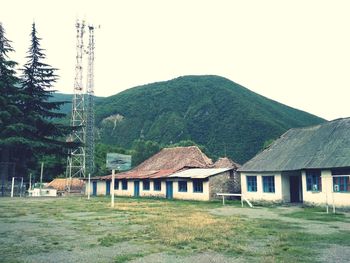 Houses on field by mountains against clear sky
