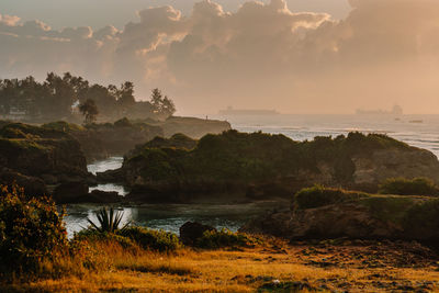 Scenic view of sea and rocks against sky during sunrise 