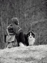 Rear view of woman with shetland sheepdog on field