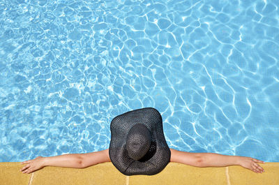 Directly above shot of woman with black hat relaxing in swimming pool