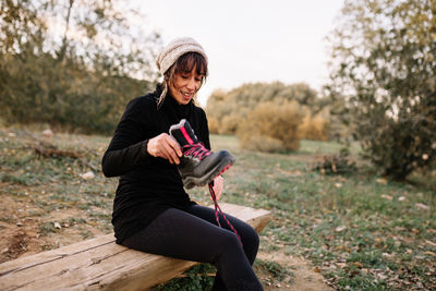 Young woman using mobile phone while sitting on land