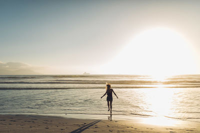 Silhouette man standing on beach against clear sky during sunset