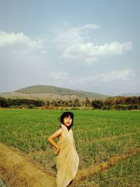 Girl covered with fabric while standing on agricultural field