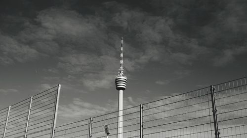 Low angle view of communications tower against cloudy sky