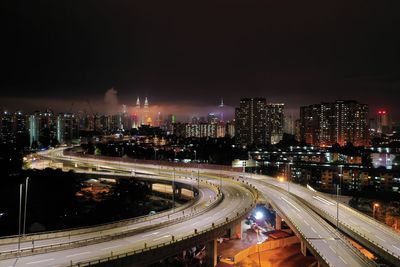 High angle view of illuminated street amidst buildings in city at night