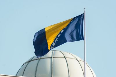 Low angle view of flag against clear blue sky