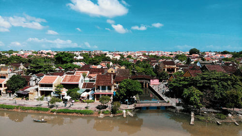 Houses by river against buildings in city against sky