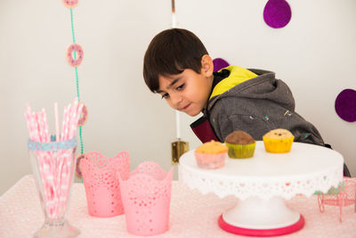 Boy standing by cupcakes on table